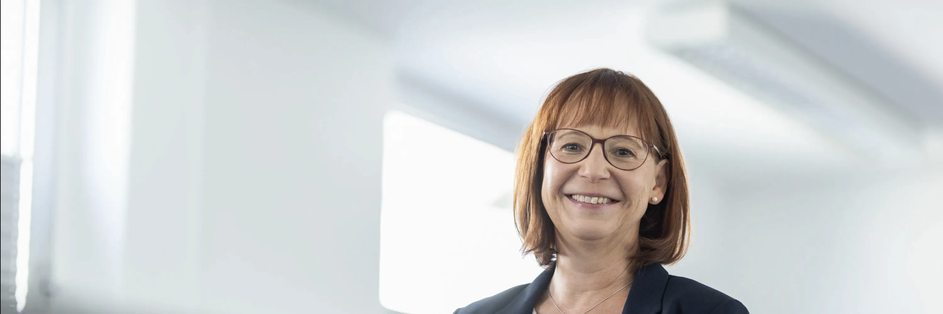 Silvia Prachnau die im Büro steht und in die Kamera lächelt